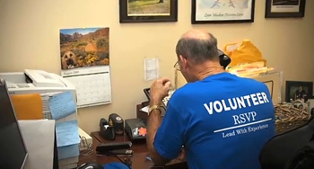 Male RSVP Volunteer at desk answering phones.